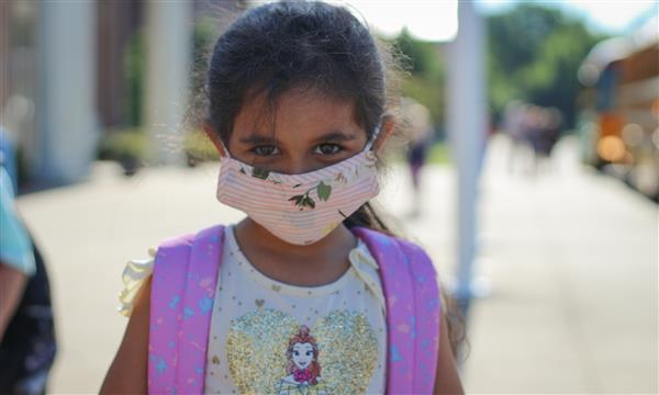girl smiles while wearing mask